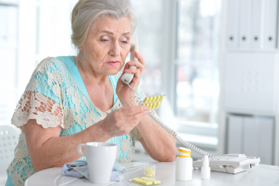 elderly woman with medication on the phone